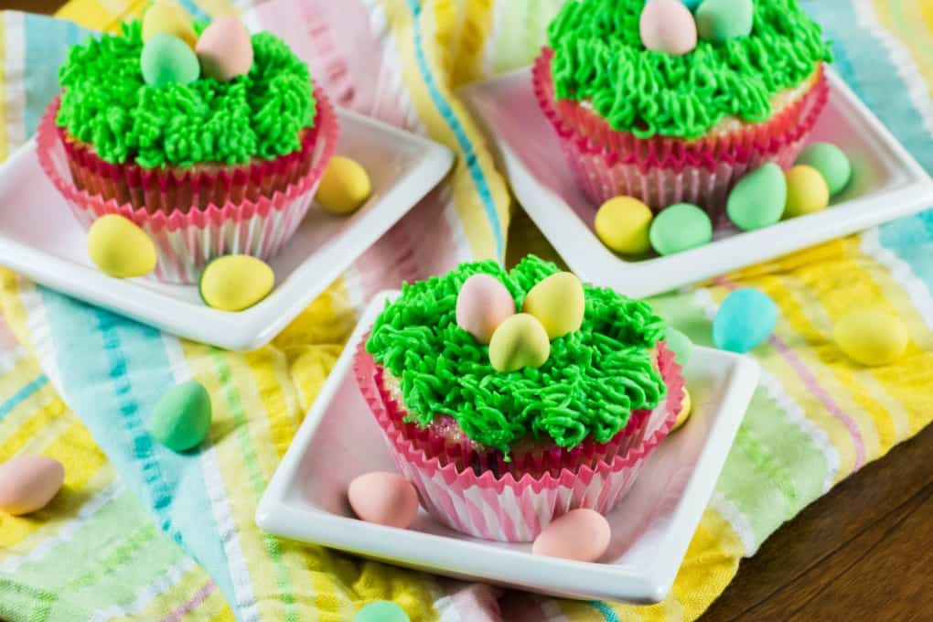 Easter Cupcakes on little white dishes with Easter eggs. 