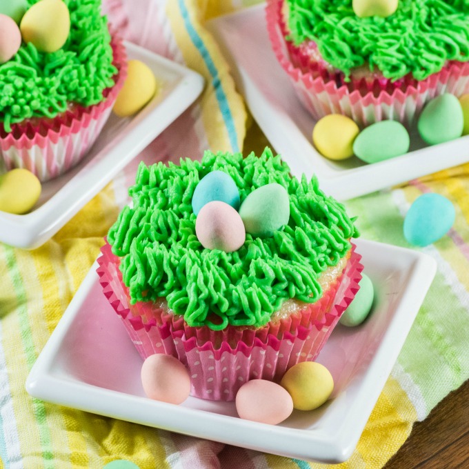 Easter Cupcakes on little white dishes with Easter eggs. 