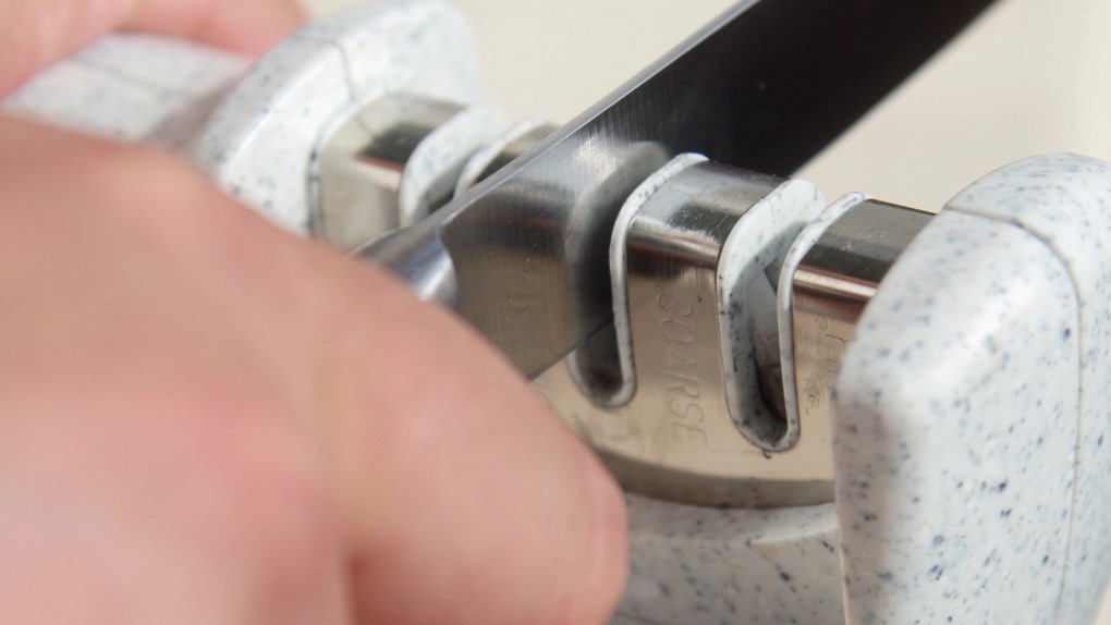 Sharpening a knife in a manual sharpener. 