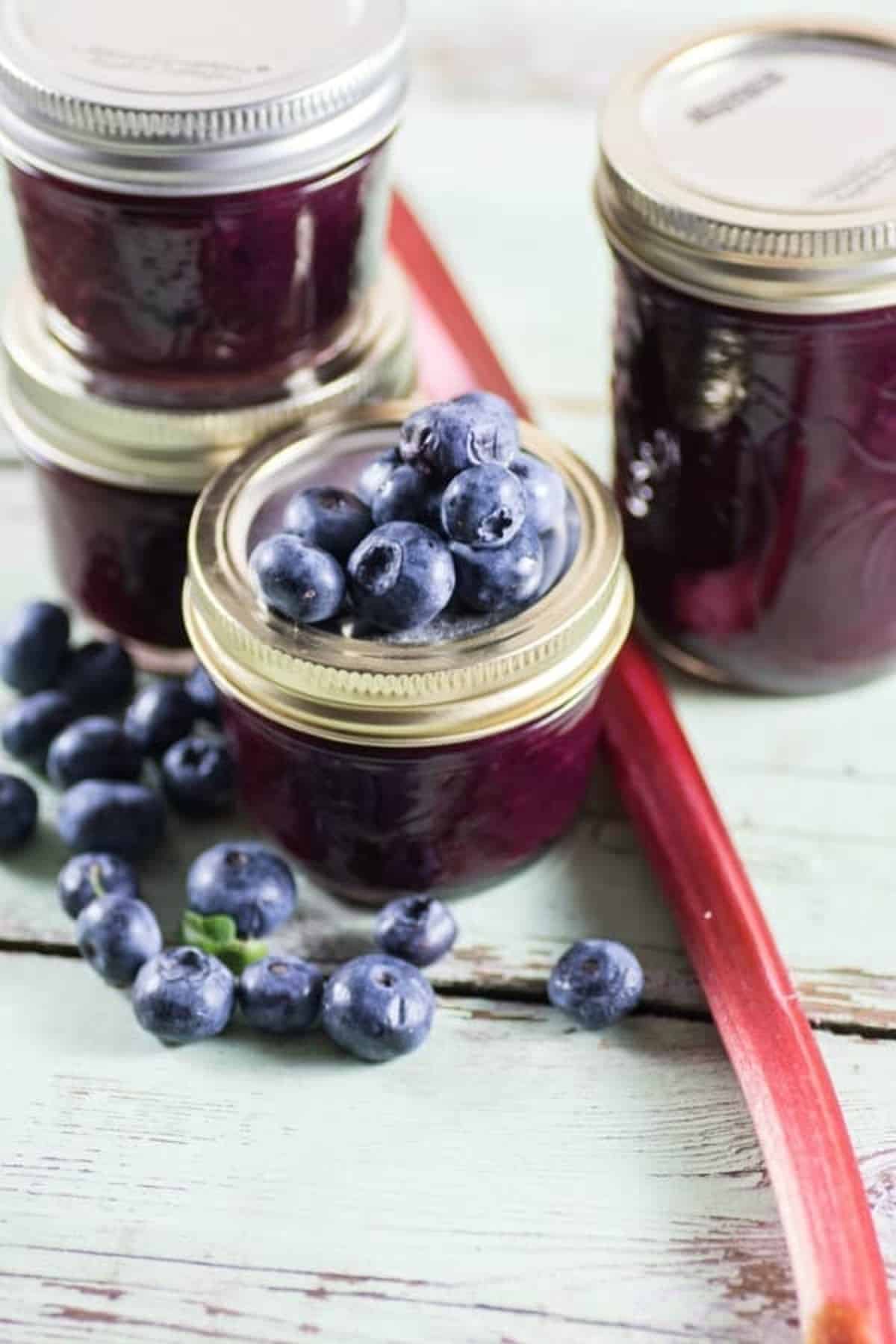 Blueberry Rhubarb Jam in jars with fresh blueberries and rhubarb.