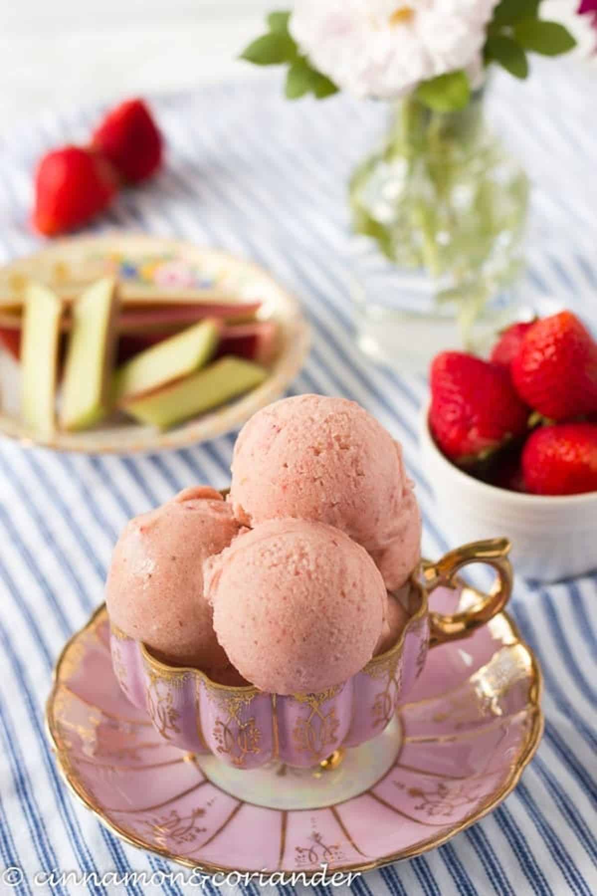 Strawberry Rhubarb Ice Cream scooped into a tea cup and saucer.