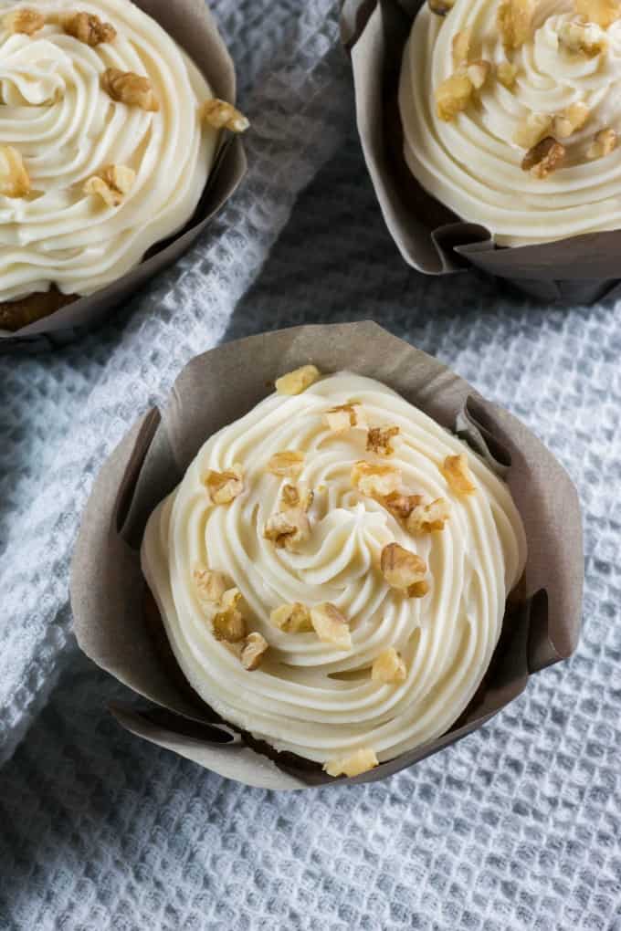 Overview of cupcakes showing cream cheese frosting and chopped walnuts. 