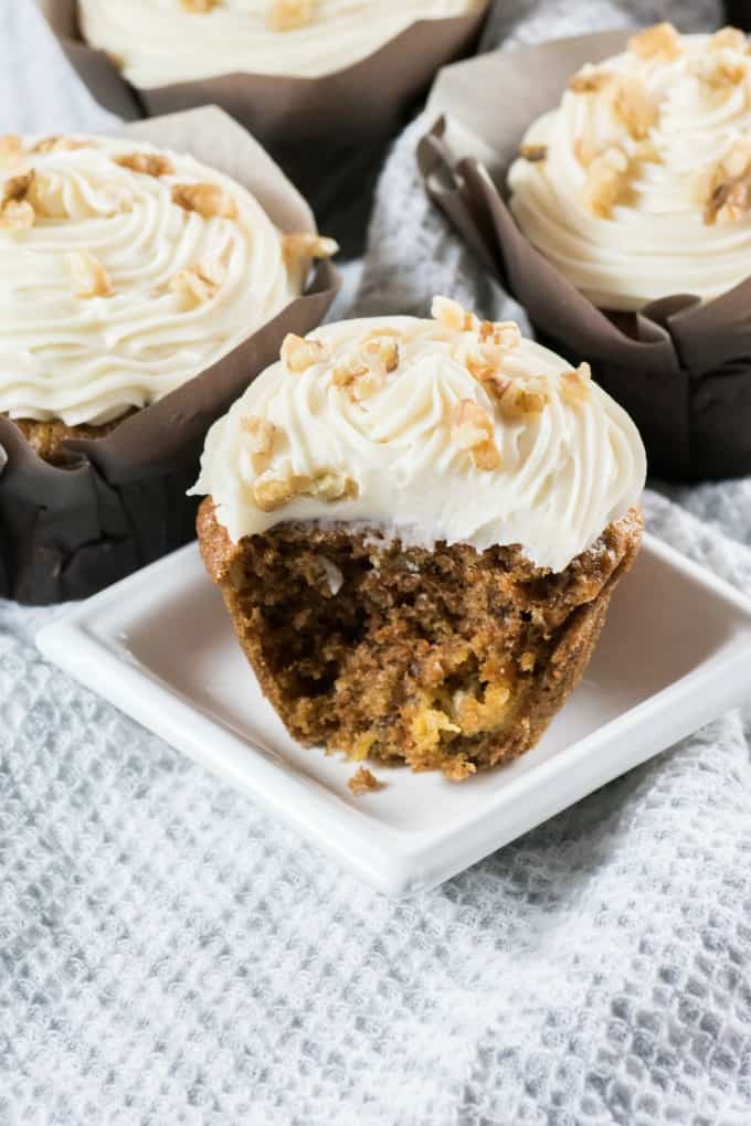 Showing a big bite out of a cupcake on a small white plate. 