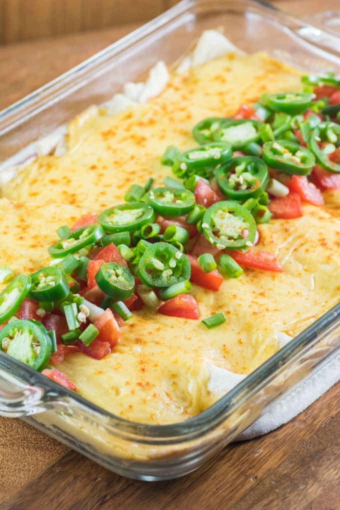 Cheesy Ground Turkey Enchiladas in a casserole dish with jalapeno tomato topping