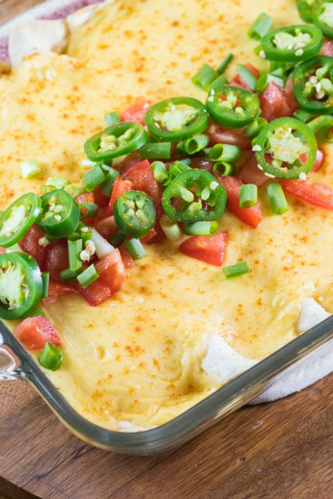 Cheesy Ground Turkey Enchiladas in a casserole dish with jalapeno tomato topping