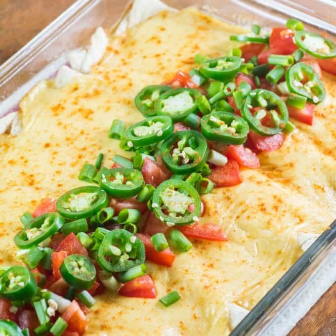 Cheesy Ground Turkey Enchiladas in a casserole dish with jalapeno tomato topping