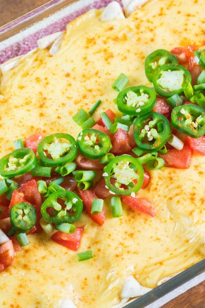 Cheesy Ground Turkey Enchiladas in a casserole dish with jalapeno tomato topping