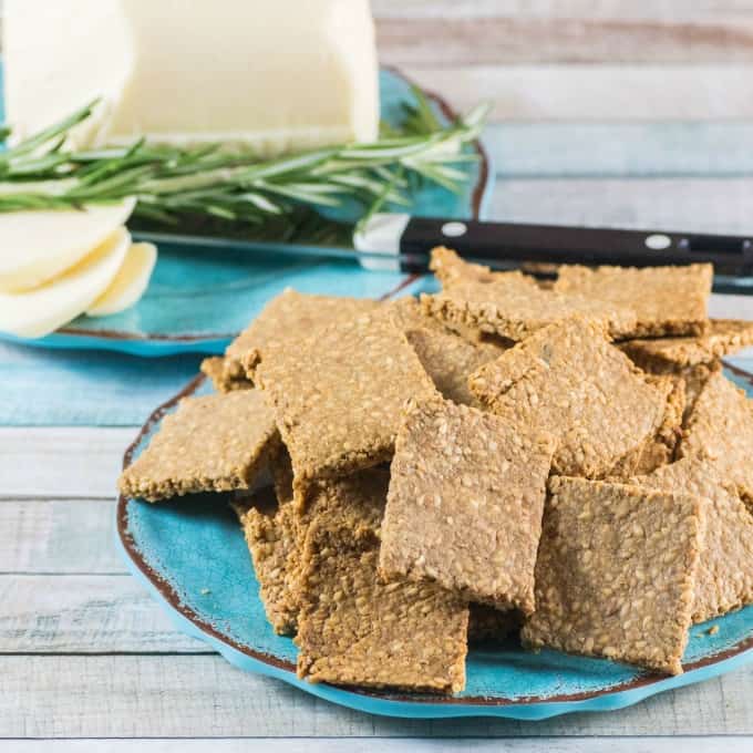 Gluten Free Crackers Recipe on a blue plate with sliced white cheese in the background. 