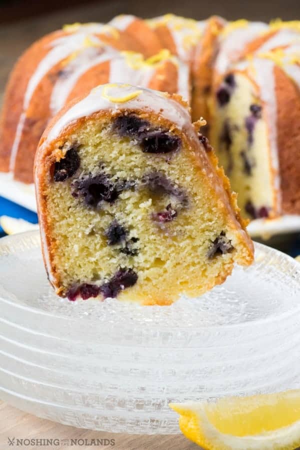 Lemon Blueberry Bundt sliced and on top of a stack of clear glass plates