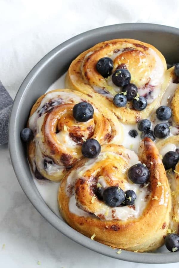 Lemon Blueberry Cheesecake Cinnamon Rolls in a round pan