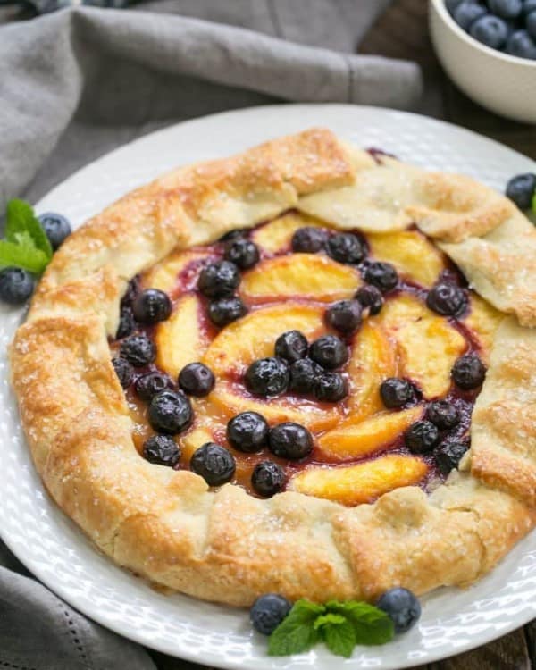 Peach Blueberry Galette on a white plate with mint and fresh blueberries