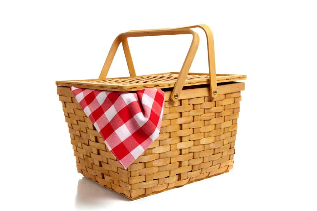 A traditional picnic basket with a checkered table cloth hanging out