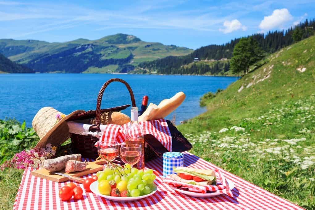 Picnic set up on a traditional checkered cloth over looking a lake and mountains