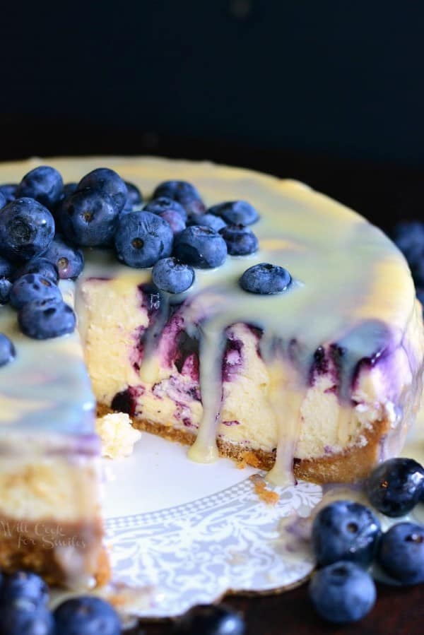 White Chocolate Blueberry Cheesecake on a white platter with fresh blueberries