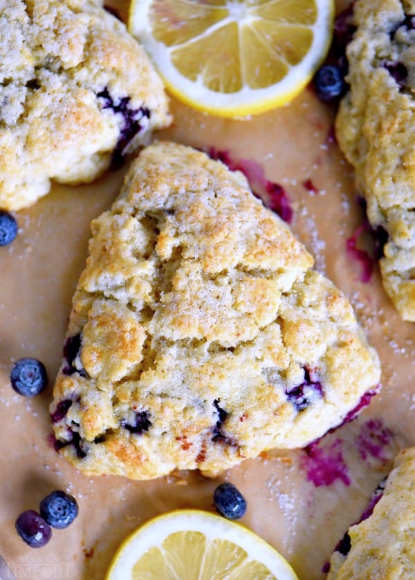 Blueberry Lemon Scones on a wooden board with fresh lemons and blueberries scattered