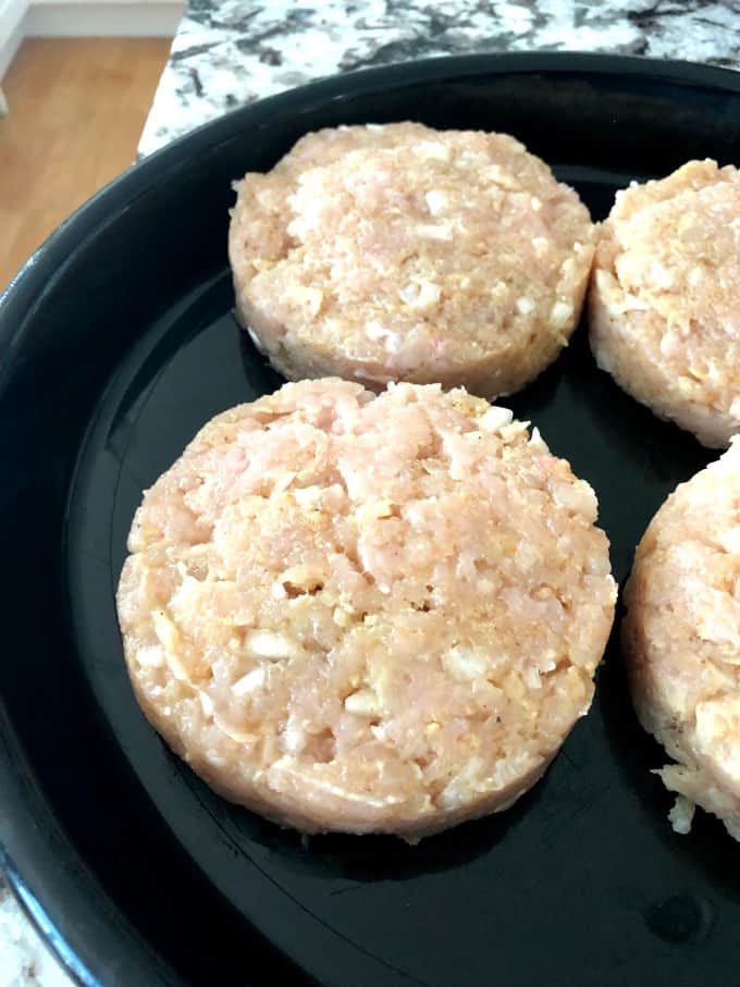 Turkey patties on a black tray ready for the grill