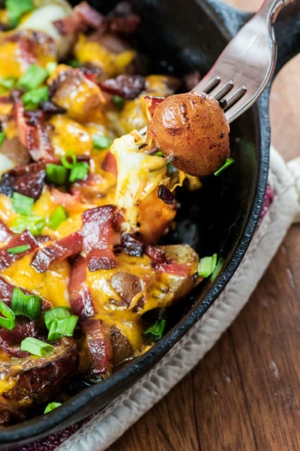 LITTLE POTATO CAMPFIRE {GRILL} HOME FRIES on a fork from a cast iron pan. 