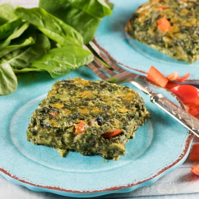 Delicious Spinach Squares on blue side plates with fresh spinach in the background. 