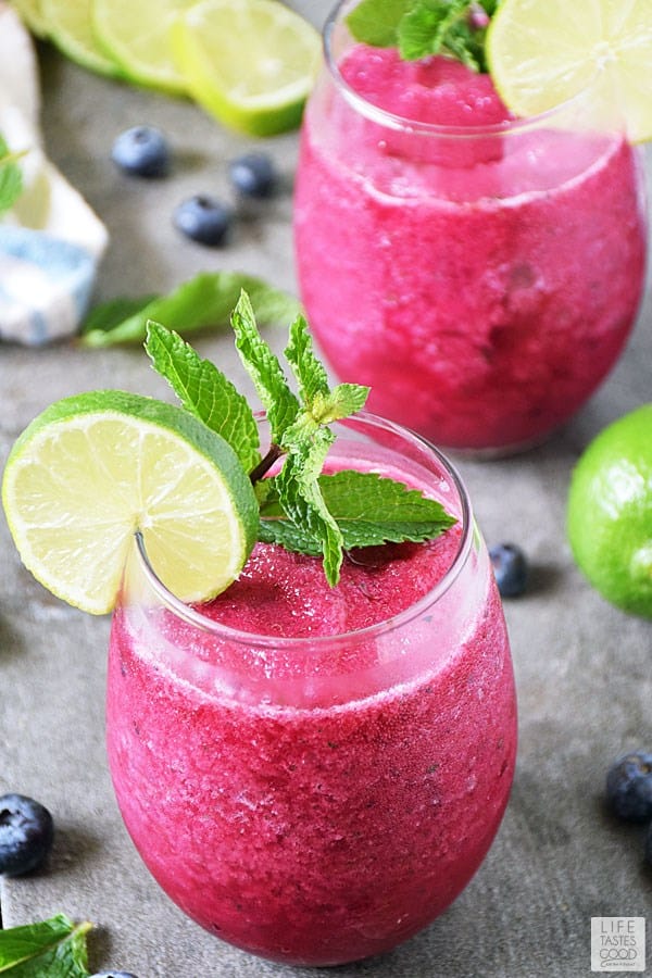 Frozen blueberry mojito in a short glass with a lime slice and mint leaves