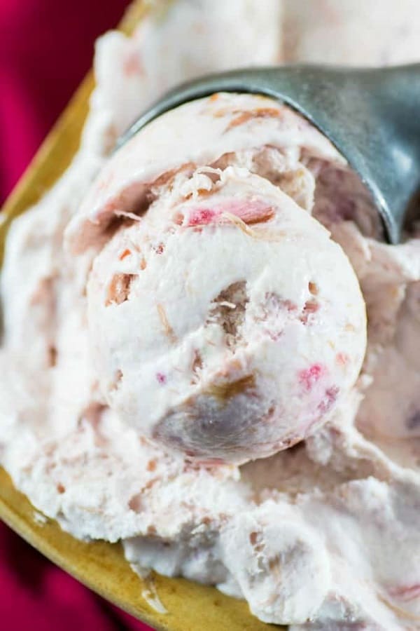 No churn rhubarb ice cream in a bowl with a silver ice cream scoop in 21 Awesome Frozen Desserts Roundup