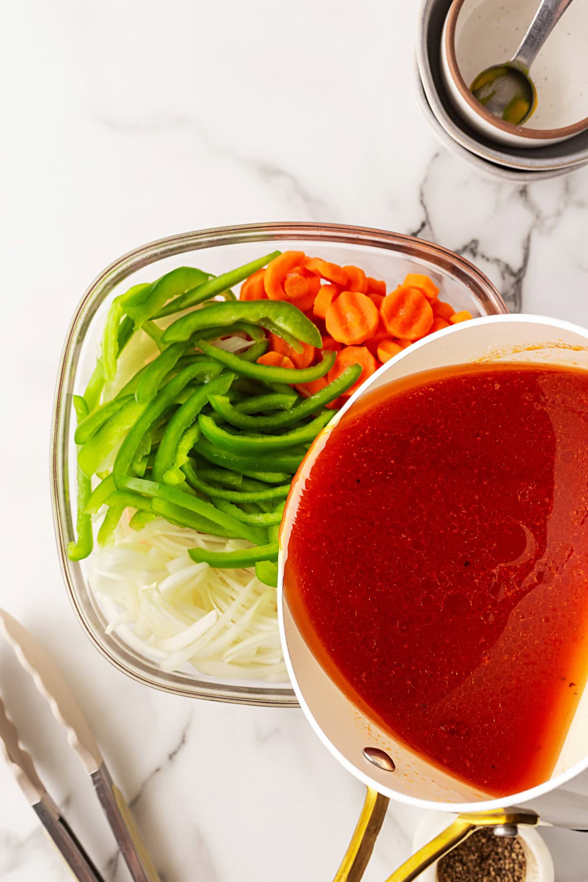 This Marinated Carrot Salad was a staple in our fridge as I grew up. It can be marinated for a long time, so it is perfect to have at the ready for any outing. Pouring the dressing on the vegetables.