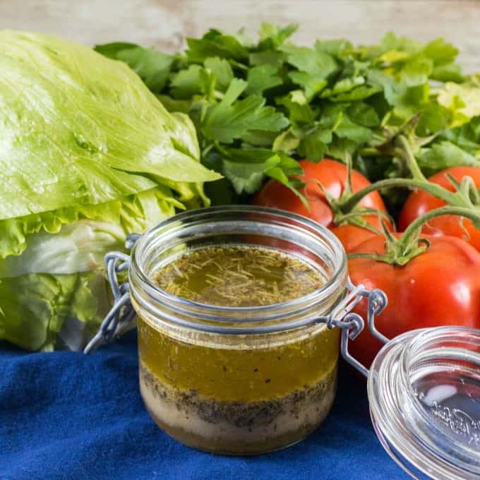 Small jar of homemade Italian dressing with tomatoes, lettuce and herbs