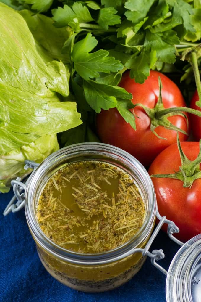 Overhead view of homemade Italian dressing in a jar with fresh produce