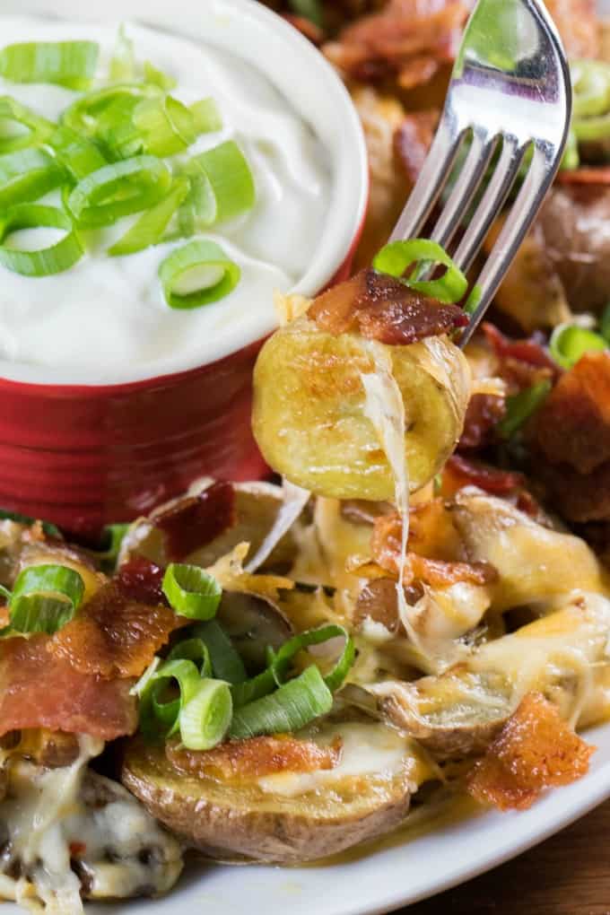 A potato, bacon and green onion on a fork