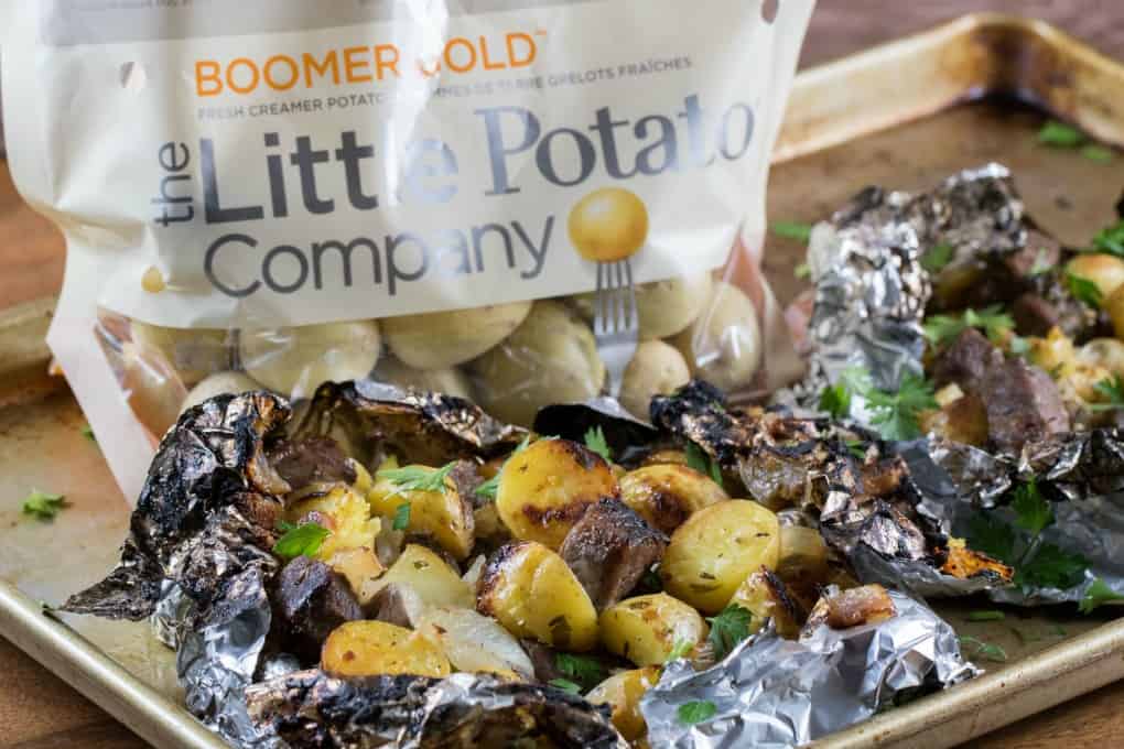 Bag of The Little Potato Company's Creamer potatoes and foil packs on a baking sheet