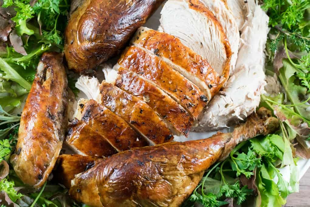 Sliced up roast turkey on a platter with greenery