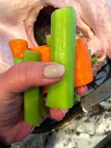 Adding in carrots and celery to a turkey