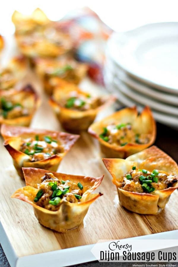 Cheesy Dijon Sausage Cups in a wooden board with white plates at the side