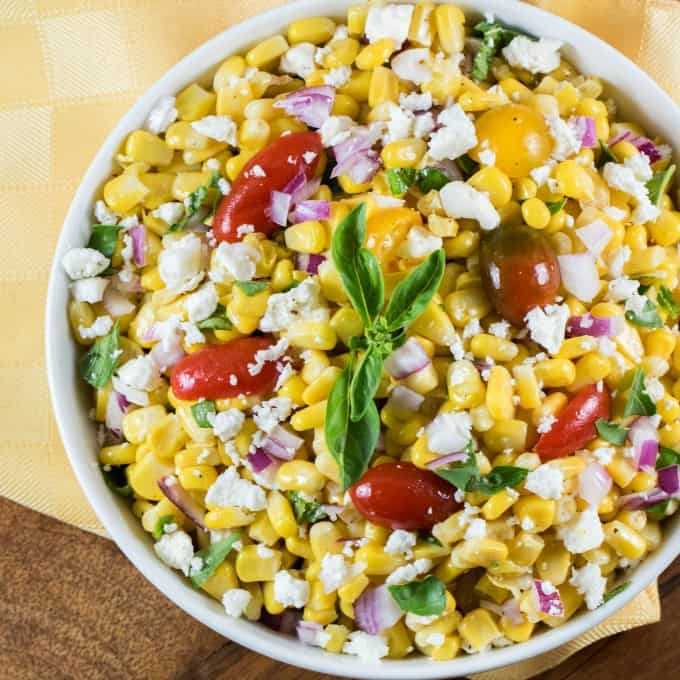 Overhead view of Cojita Corn Salad Recipe in a white bowl with a yellow napkin underneath. 