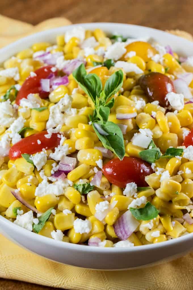 Close up of Cotija Corn Salad Recipe in a white bowl over a yellow napkin