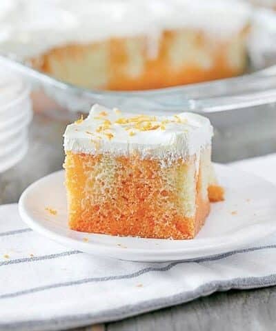 Square slice of orange creamsicle poke cake on a plate