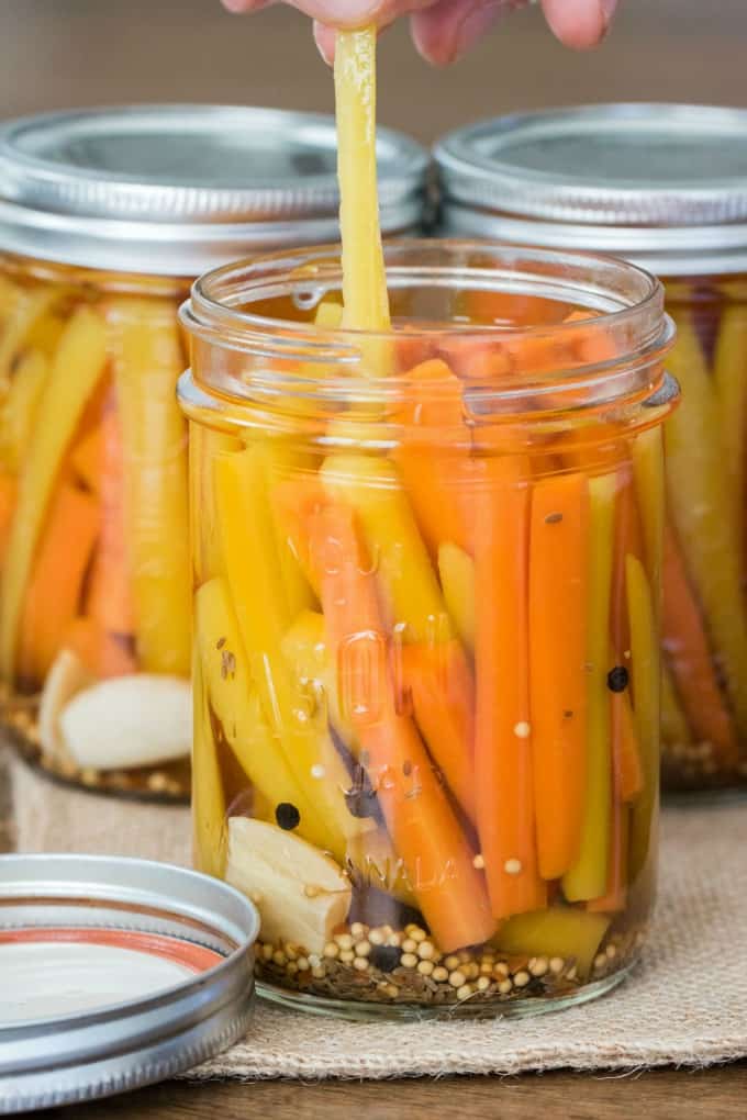 Taking out a yellow carrot from a jar of pickled carrots