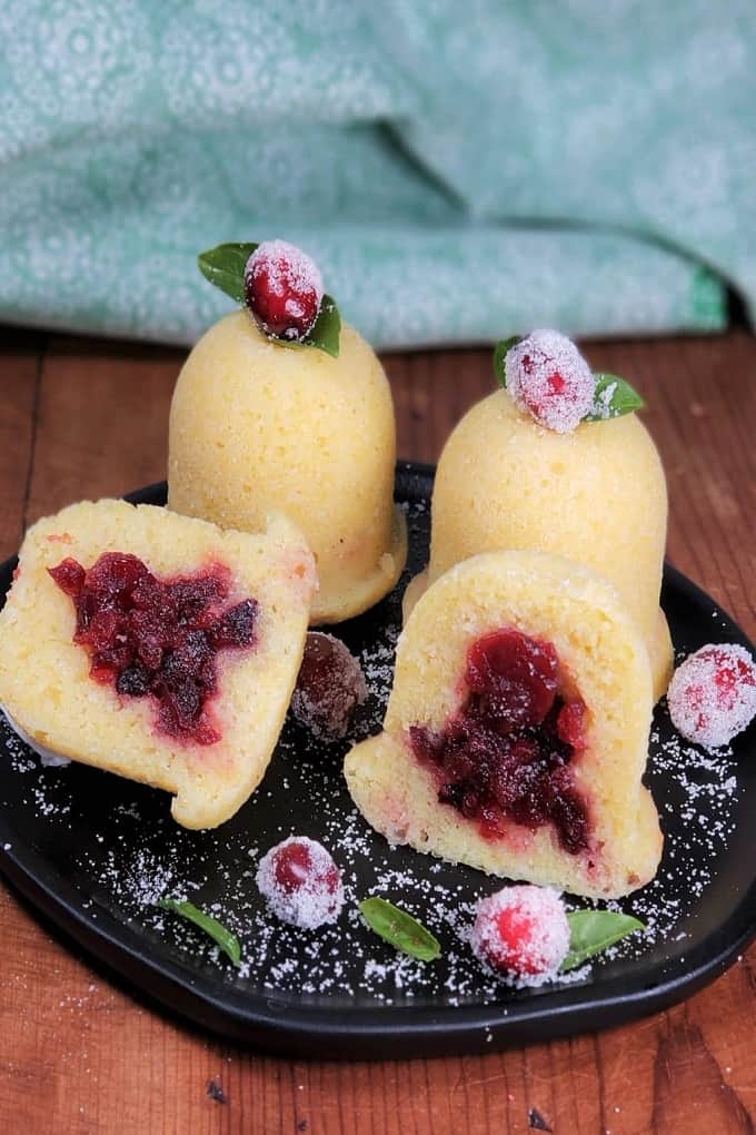 Cranberry cornbread jingle bells on a black plate with sugared cranberries