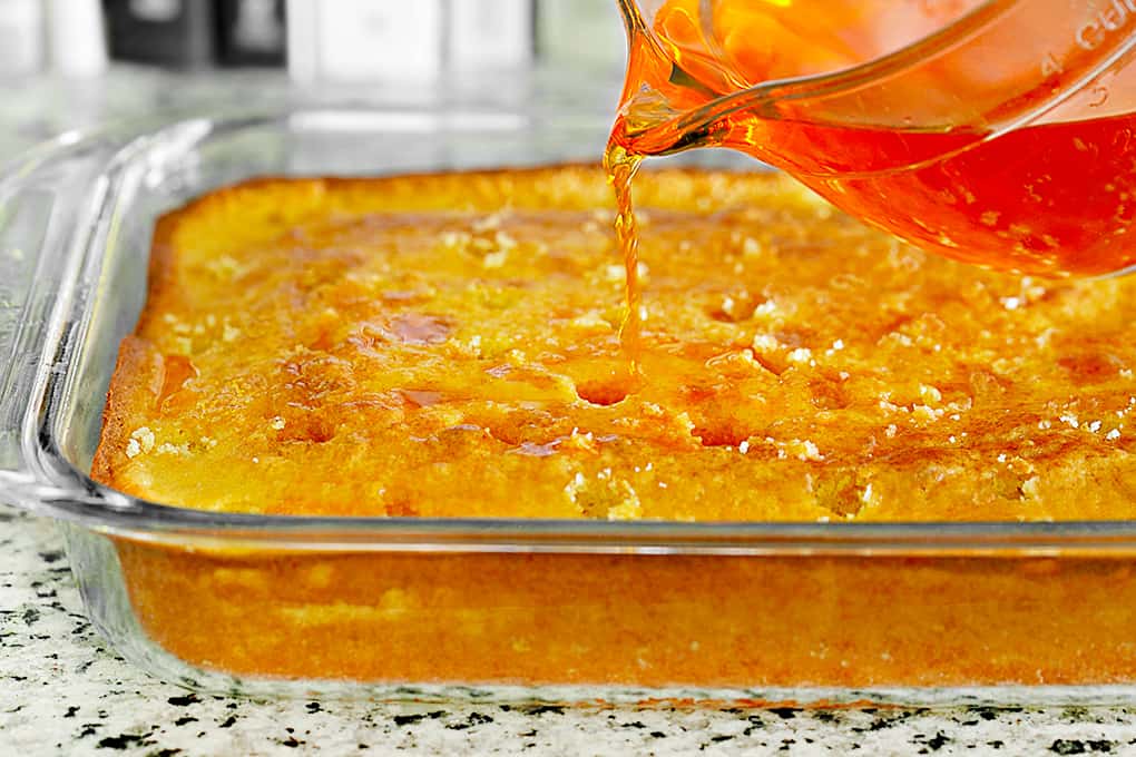 Pouring orange jello on a cake