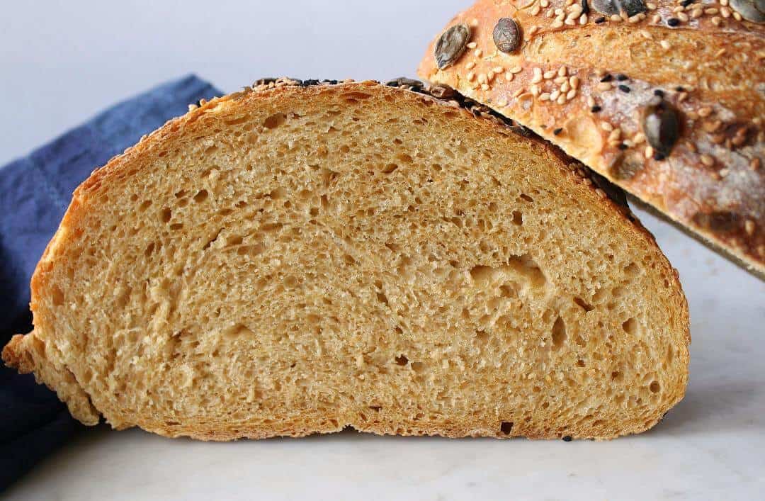Pumpkin No Knead Bread - A bread boule sliced in half to show the interior texture of the loaf.
