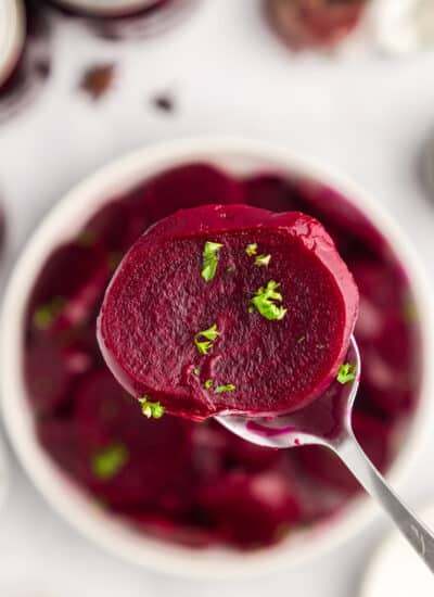 Sliced beet on a spoon with chopped parsley on top.
