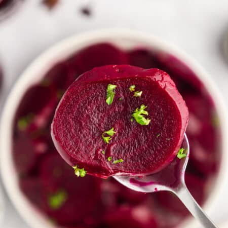 Sliced beet on a spoon with chopped parsley on top.