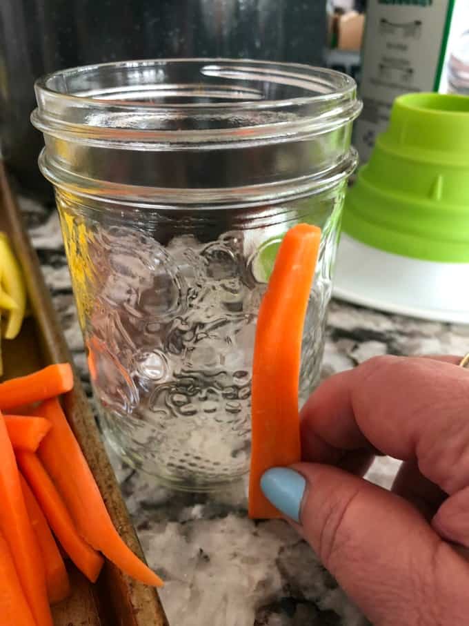 Measuring a think stick of a carrot to see if it fits in a jar