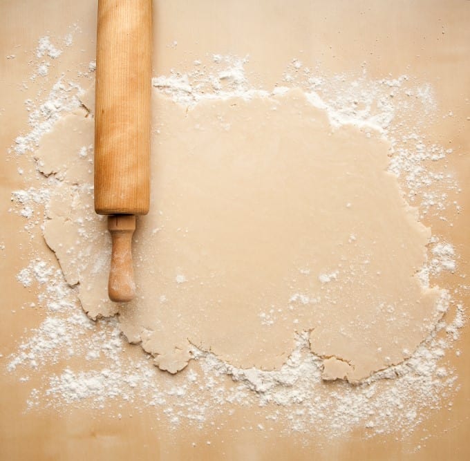 Pie dough on a floured surface with a rolling pin