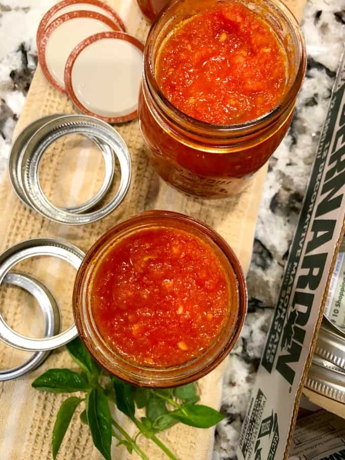 Overhead view of jars filled with tomato sauce with lids and rims