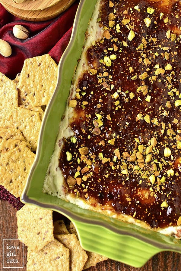 Warm Fig and Prosciutto Goat Cheese Dip in a green dish with crackers