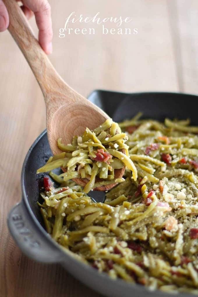 Green beans with bacon in a cast iron pan with a wooden spoon