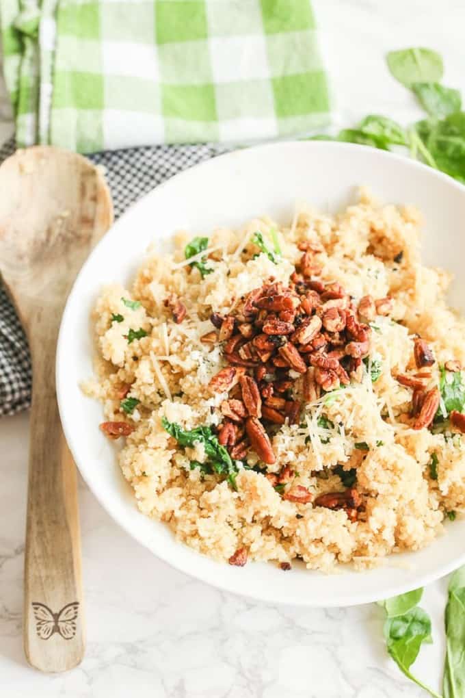 Parmesan quinoa in a white serving bowl with a wooden serving spoon