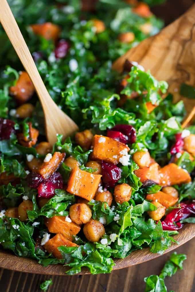 Roasted Butternut squash salad with chick peas and cranberries in a wooden salad bowl and wooden tongs