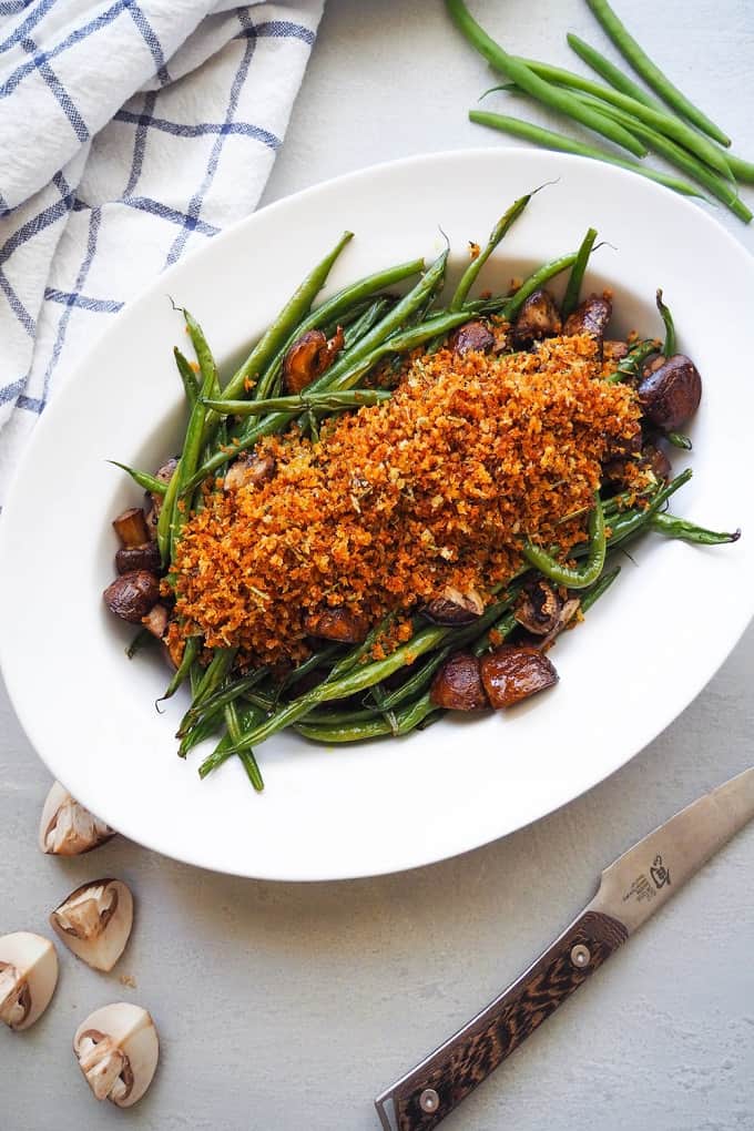 Roasted green bean and mushrooms with herbed breadcrumbs on a white serving plate 