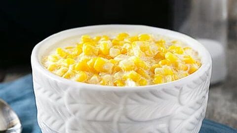 Slow Cooker Creamed Corn. Bowl of creamed corn sitting in front of slow cooker
